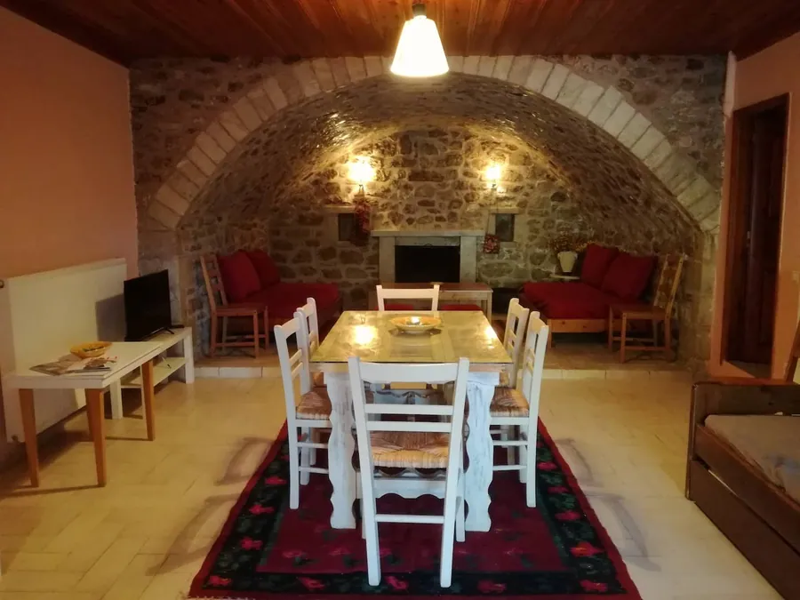 Πέτρινος θόλος με τραπεζαρία, κόκκινους καναπέδες και τζάκι στο βάθος